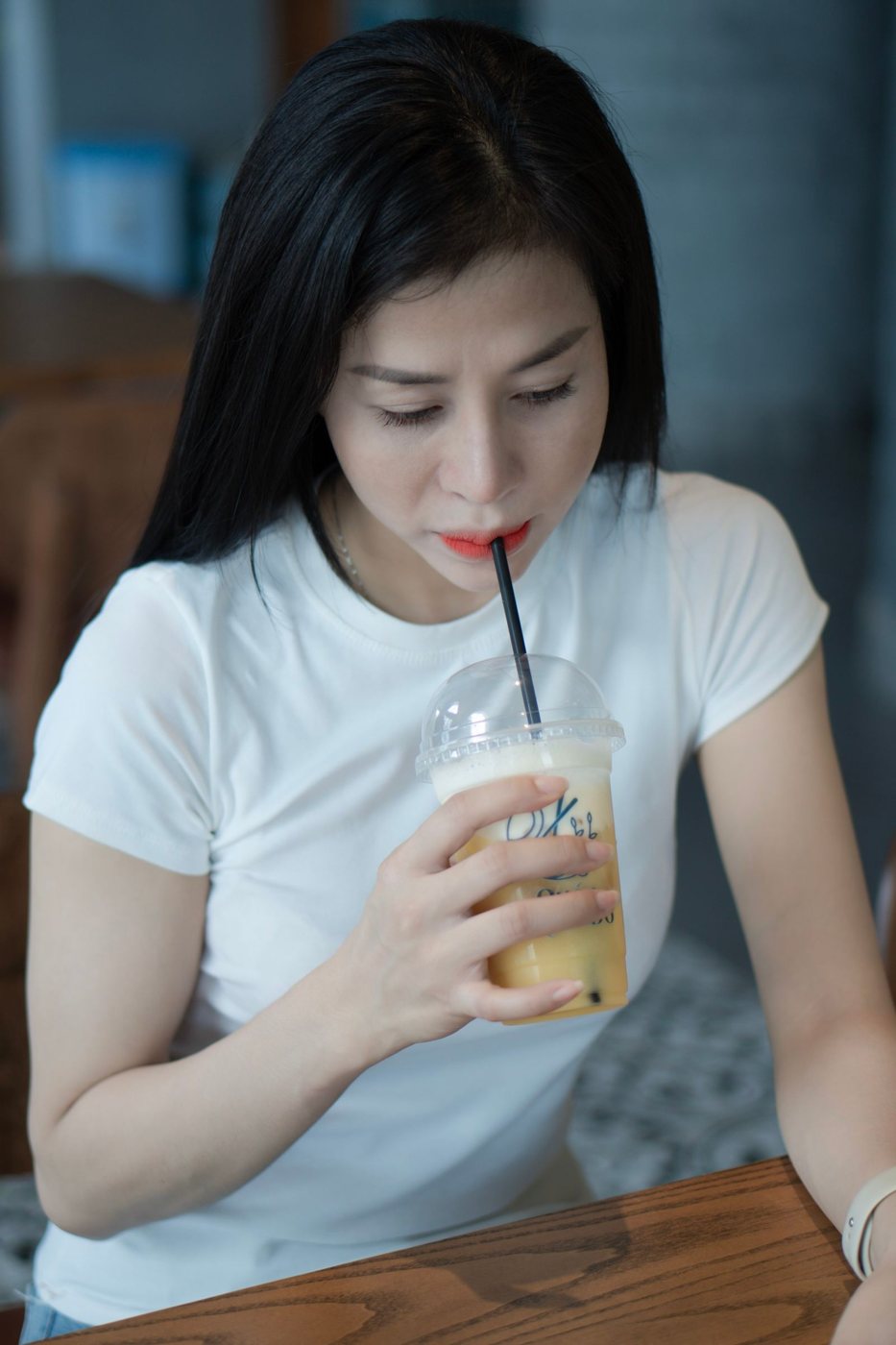 Mulher a beber uma bebida com palhinha num café